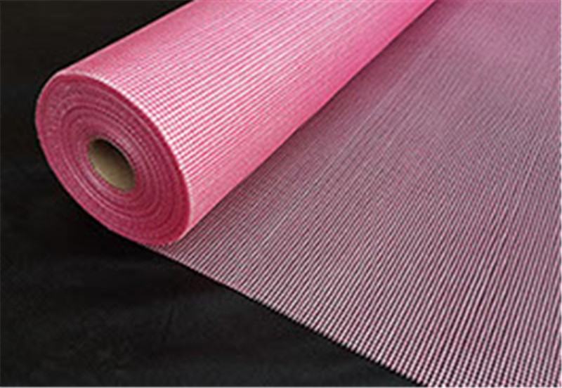 A reinforcing mesh which is made from woven fibreglass yarns and coated with an alkaline resistant latex. This coating prevents the alkaline present in cements from degrading the glass fibre, resulting